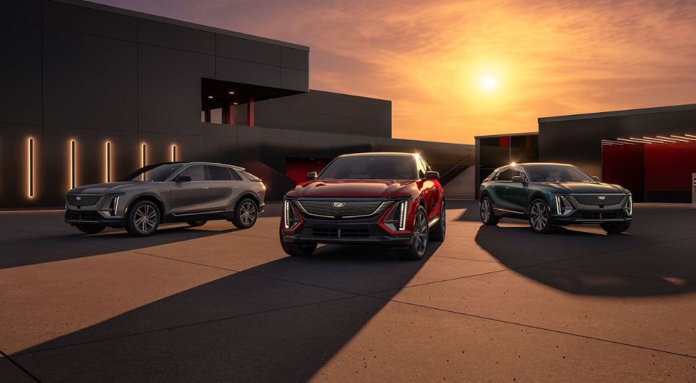 A grey, a red, and a green 2024 Cadillac LYRIQ for sale near Eagle Lake are shown parked during a sunset.
