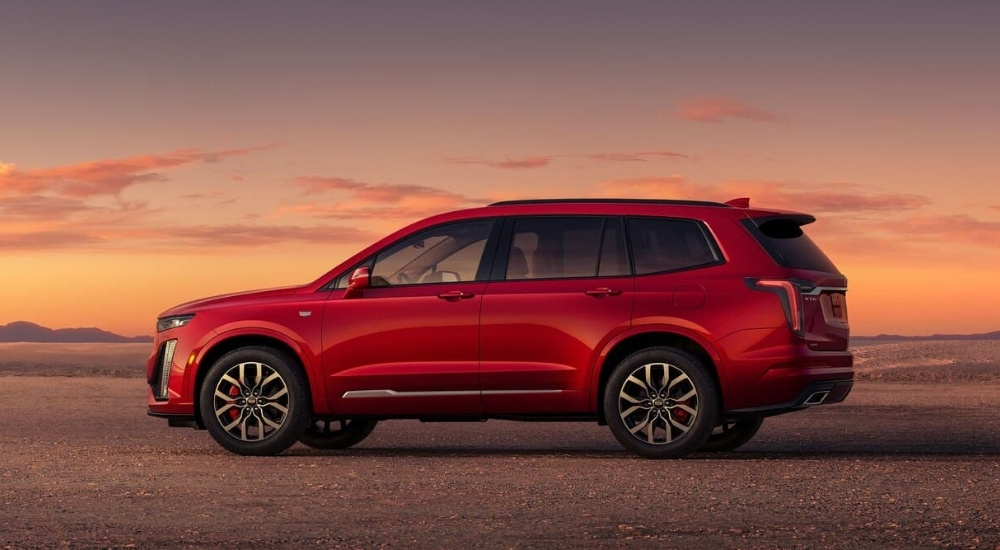 A red 2025 Cadillac XT6 for sale is parked in an open area.