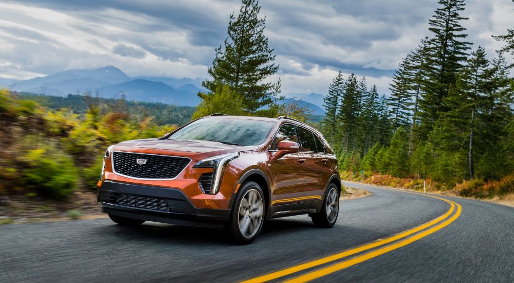 An orange 2019 Cadillac XT4 is shown rounding a corner after looking at used SUVs for sale.