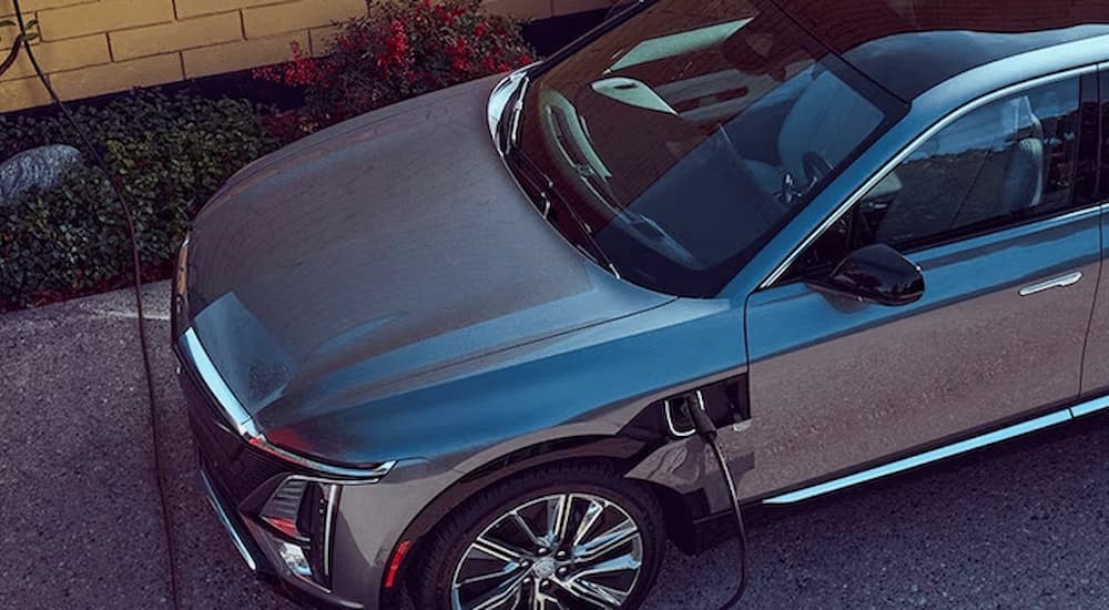 A silver 2024 Cadillac LYRIQ for sale is shown charging at an EV charger.