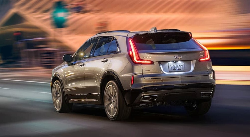 A silver 2023 Cadillac XT4 is shown from the rear driving on a city road at night after leaving a Cadillac dealer near Waseca.