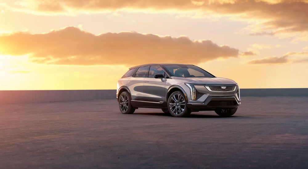 A silver 2025 Cadillac OPTIQ Sport parked outside at sunset.