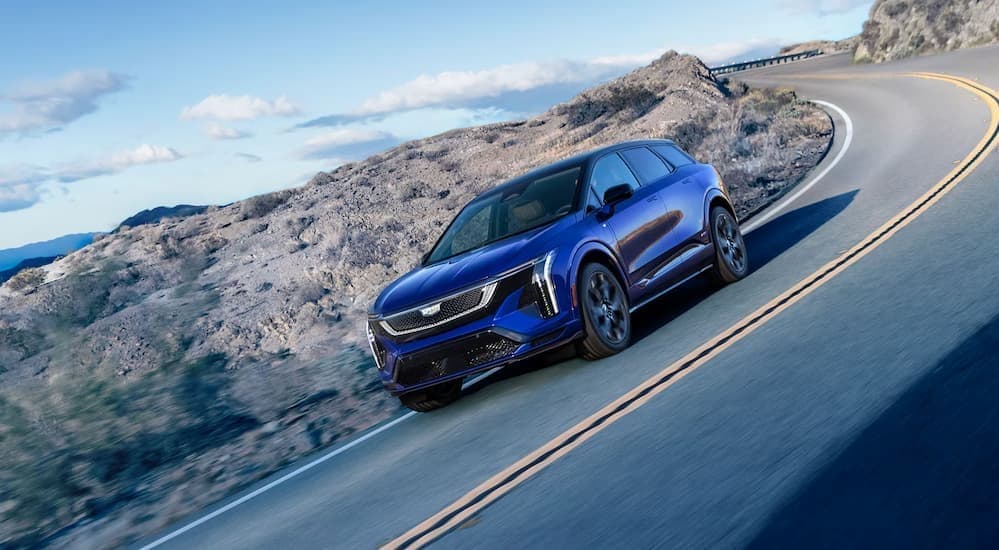 A blue 2026 Cadillac OPTIQ driving on a highway.