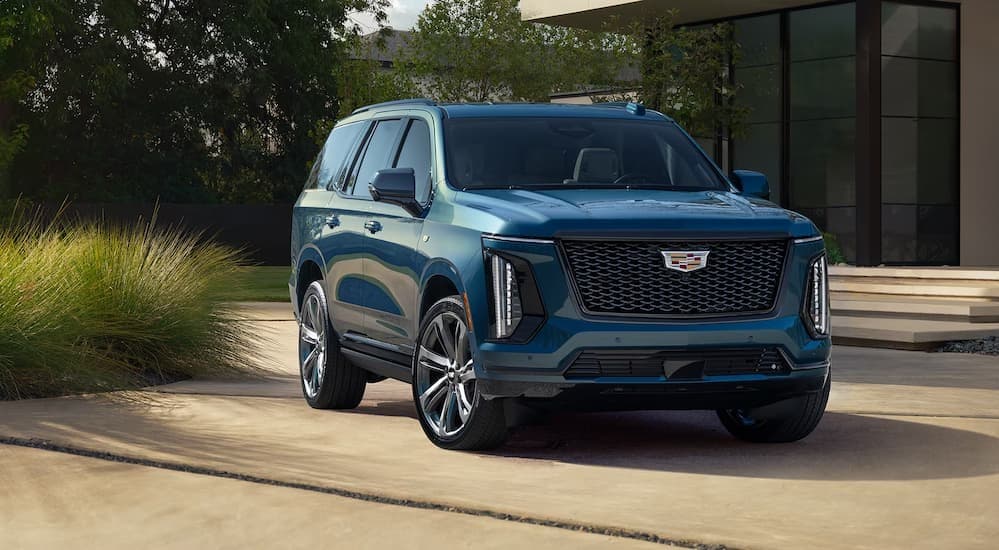 A green 2026 Cadillac Escalade parked near a house.