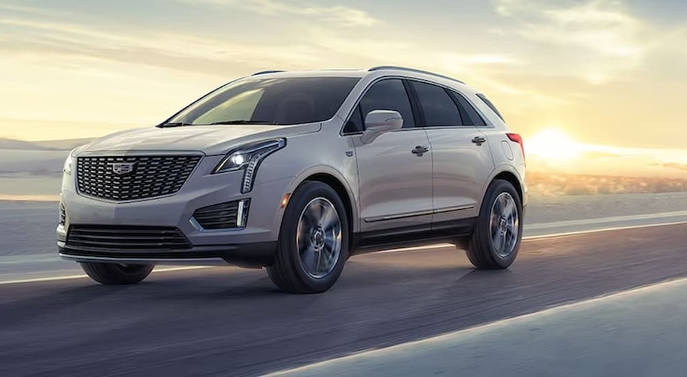 White 2024 Cadillac XT5 driving on sand.