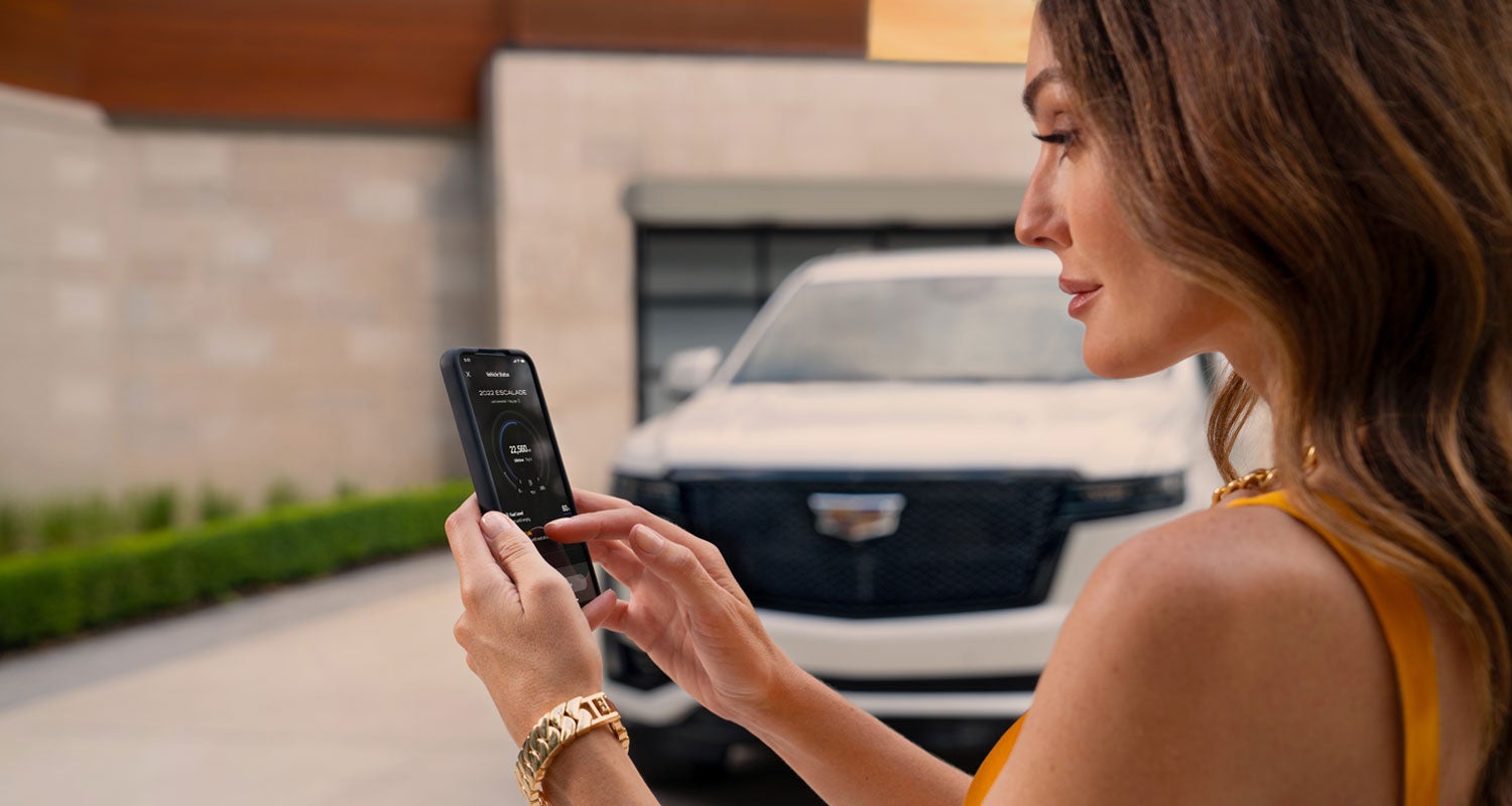 lady checking her mobile with a Cadillac vehicle background | Snell Motors in Mankato MN