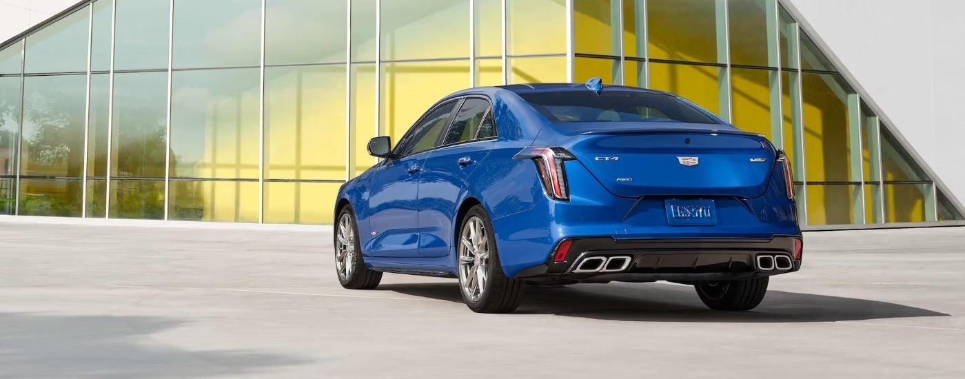 Blue 2022 Cadillac CT4-V Blackwing from the rear in front of a glass building.