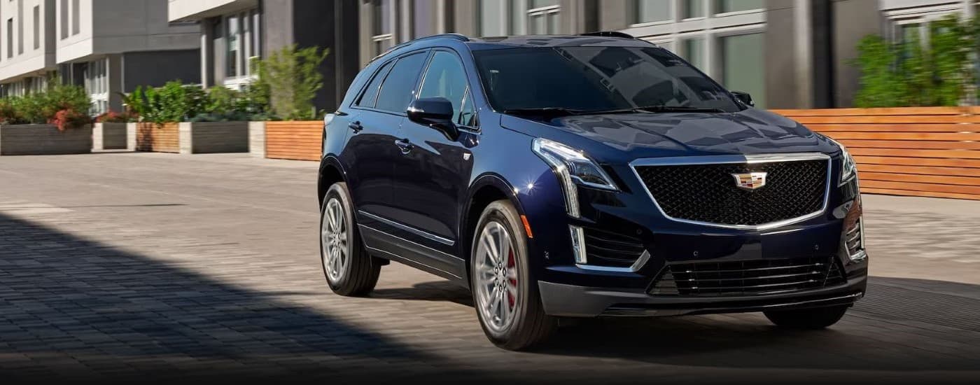 Black 2023 Cadillac XT5 driving in a residental neighborhood.