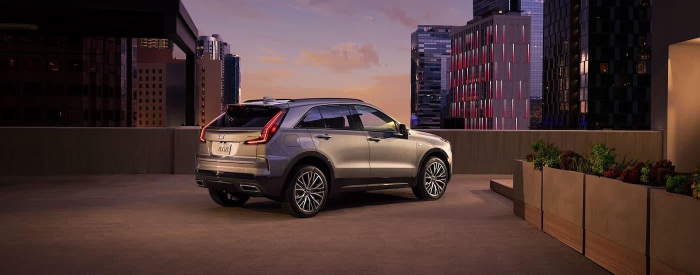 A silver 2024 Cadillac XT4 is parked on top of a city rooftop parking area.