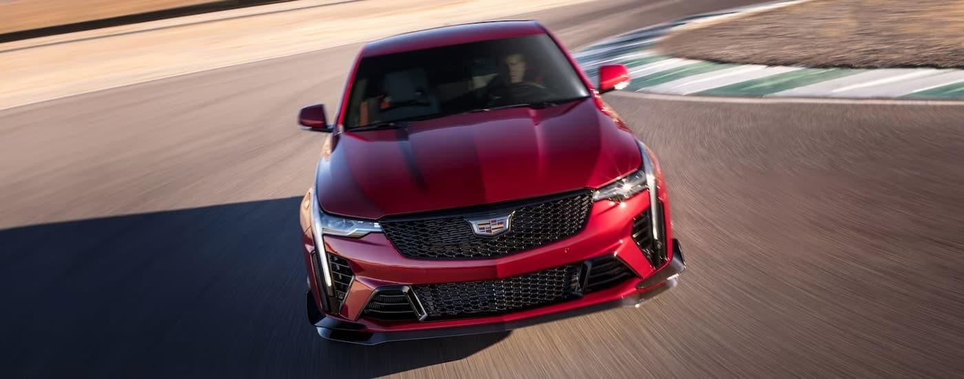 A red 2023 Cadillac CT4-V is shown from the front driving on a track after leaving a Cadillac dealer.