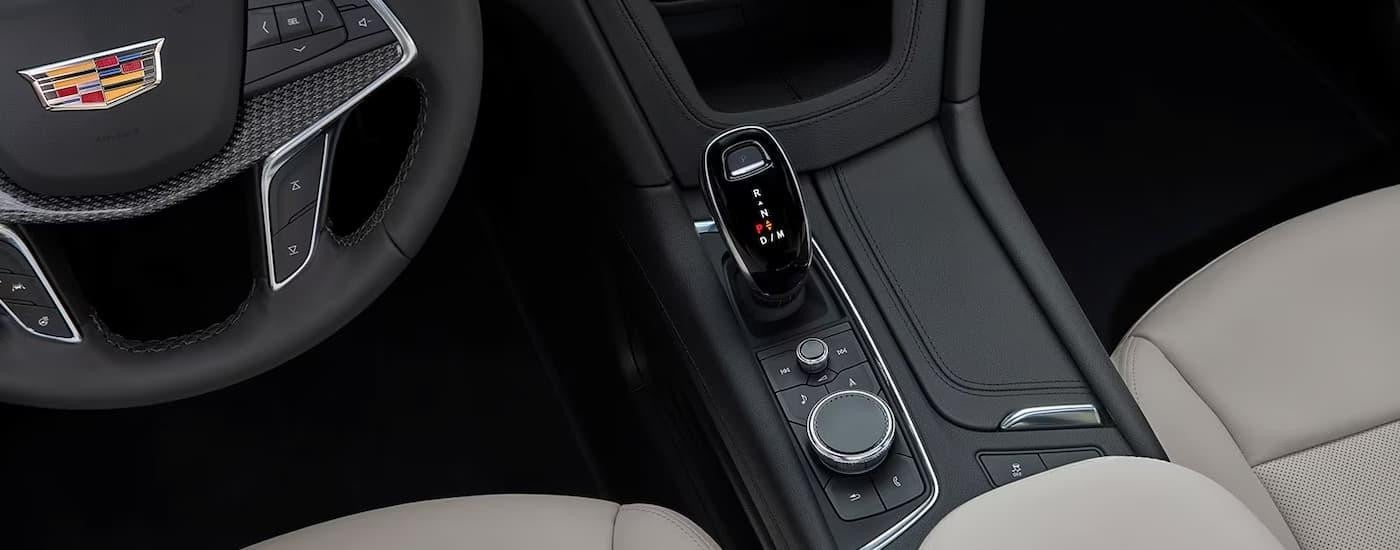 The black and grey interior of a 2023 Cadillac XT5 shows the center console and steering wheel.