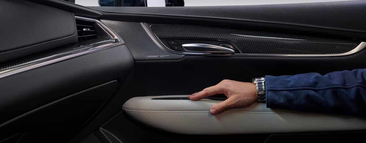 A man is resting his arm on the door inside of a 2025 Cadillac XT5.