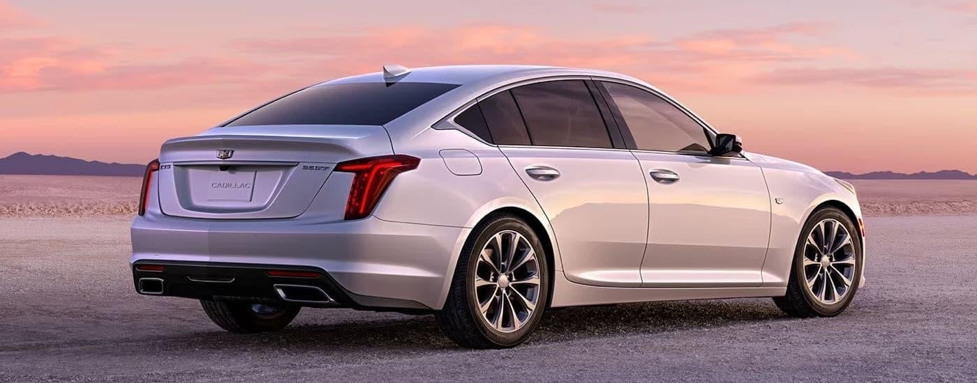 A silver 2023 Cadillac CT5 is shown from a rear angle parked on a gravel lot.