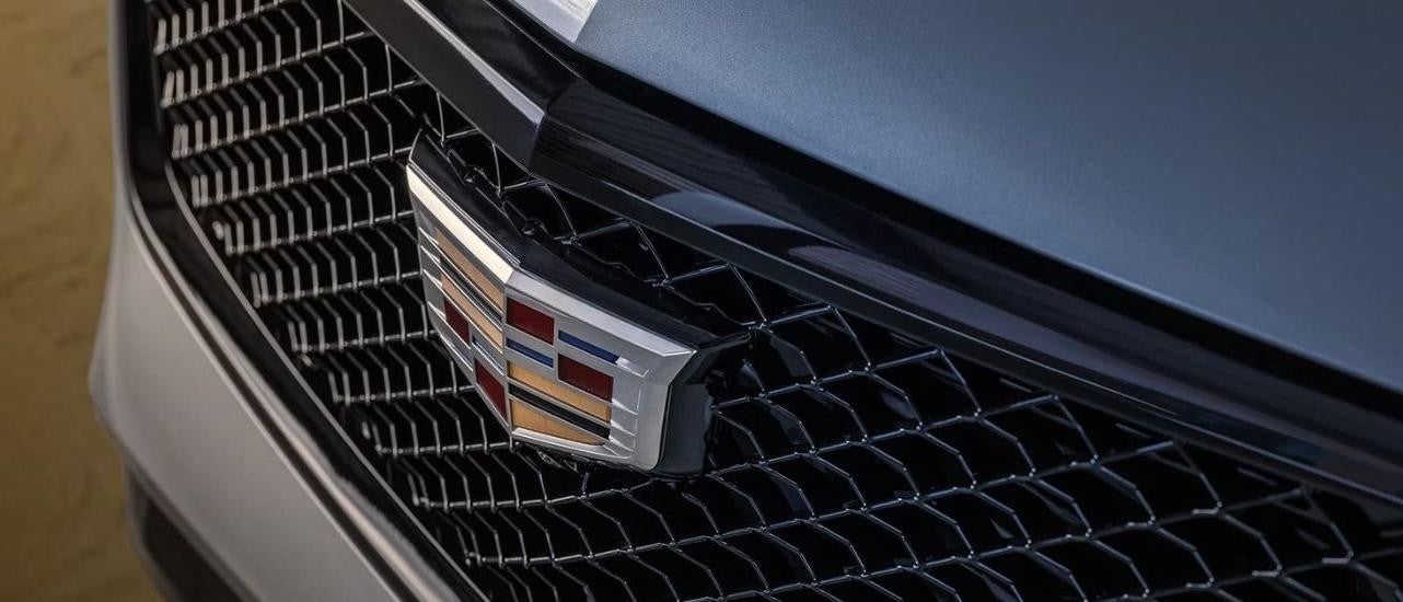 A close up shows the Cadillac badge on the grille of a white 2024 Cadillac XT4.