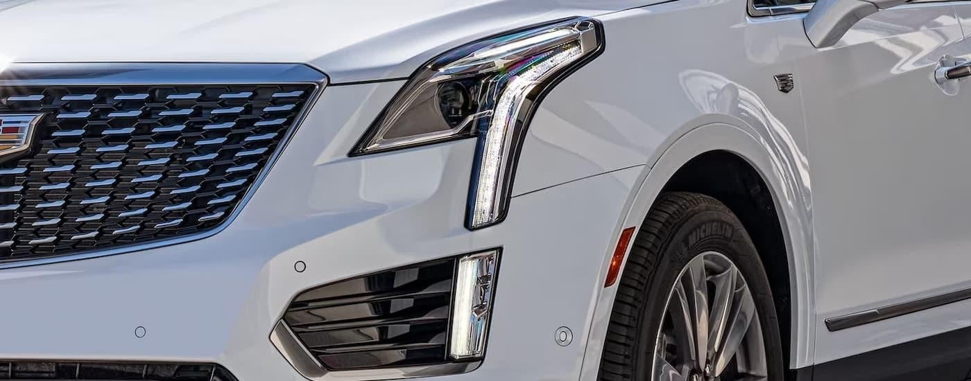 A close up of the headlight of a white 2023 Cadillac XT5 is shown.