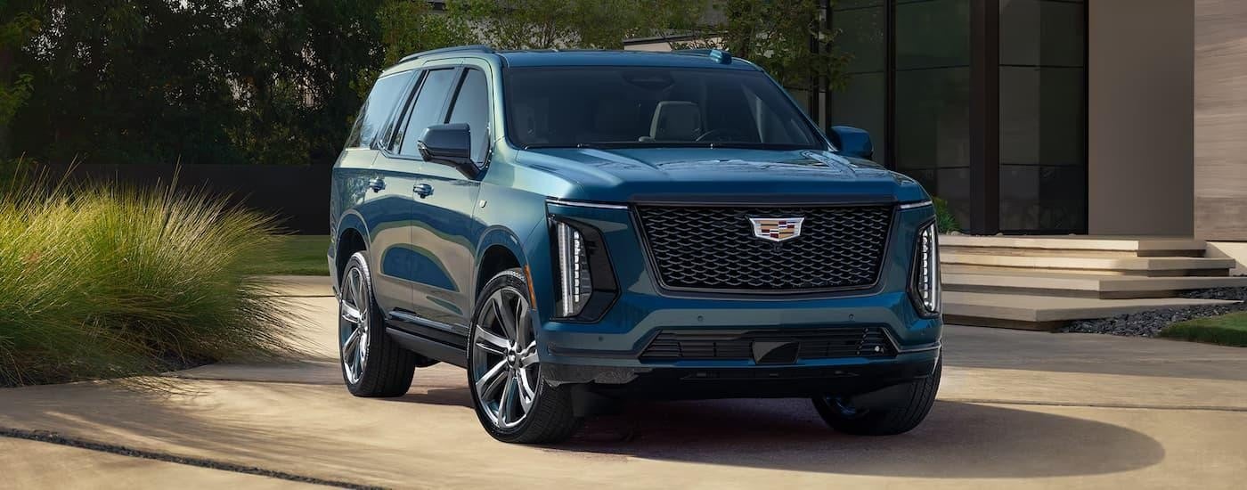 A blue 2025 Cadillac Escalade is parked in a driveway.