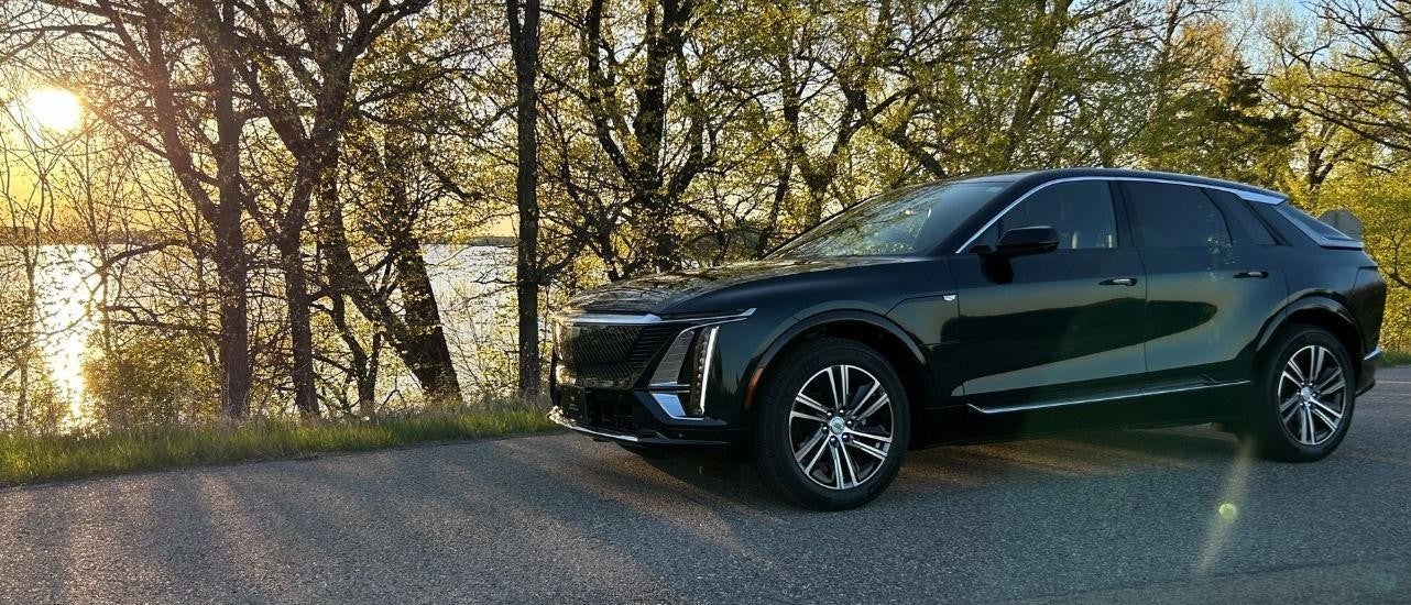 A black 2024 Cadillac LYRIQ is shown near a lake.