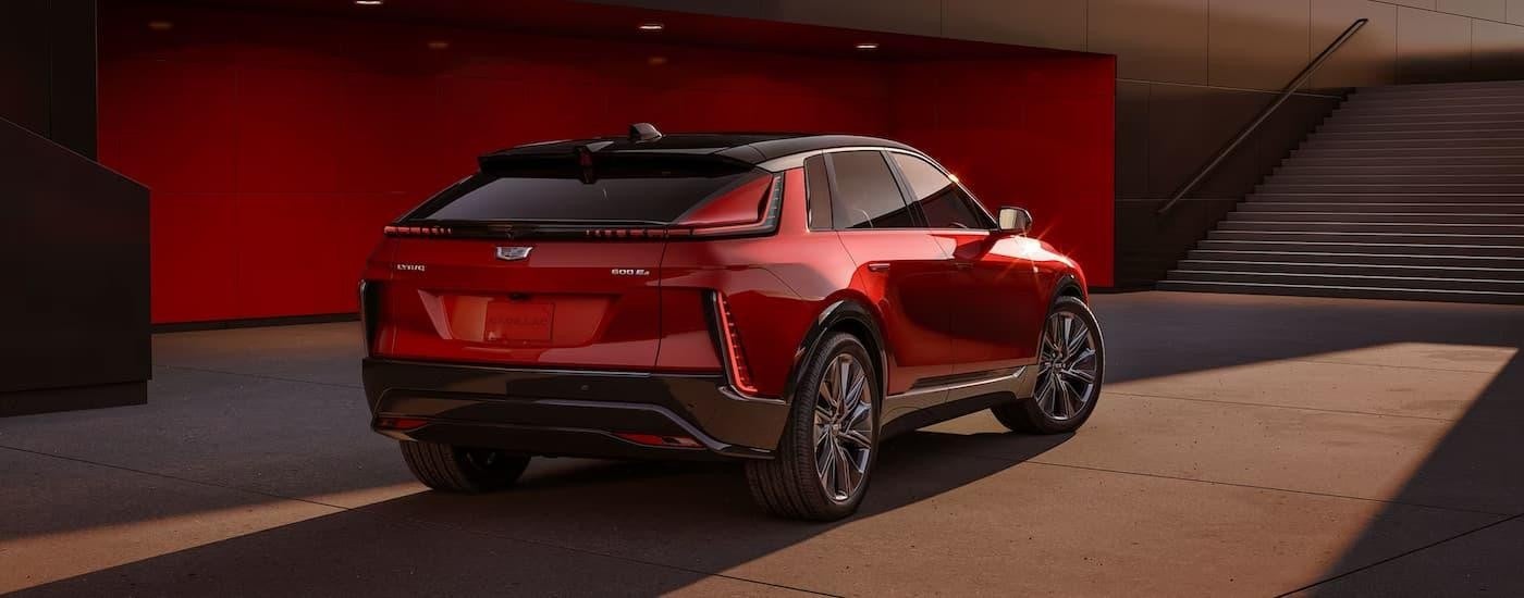 A red 2024 Cadillac LYRIQ is shown from the rear while parked near a set of stairs.
