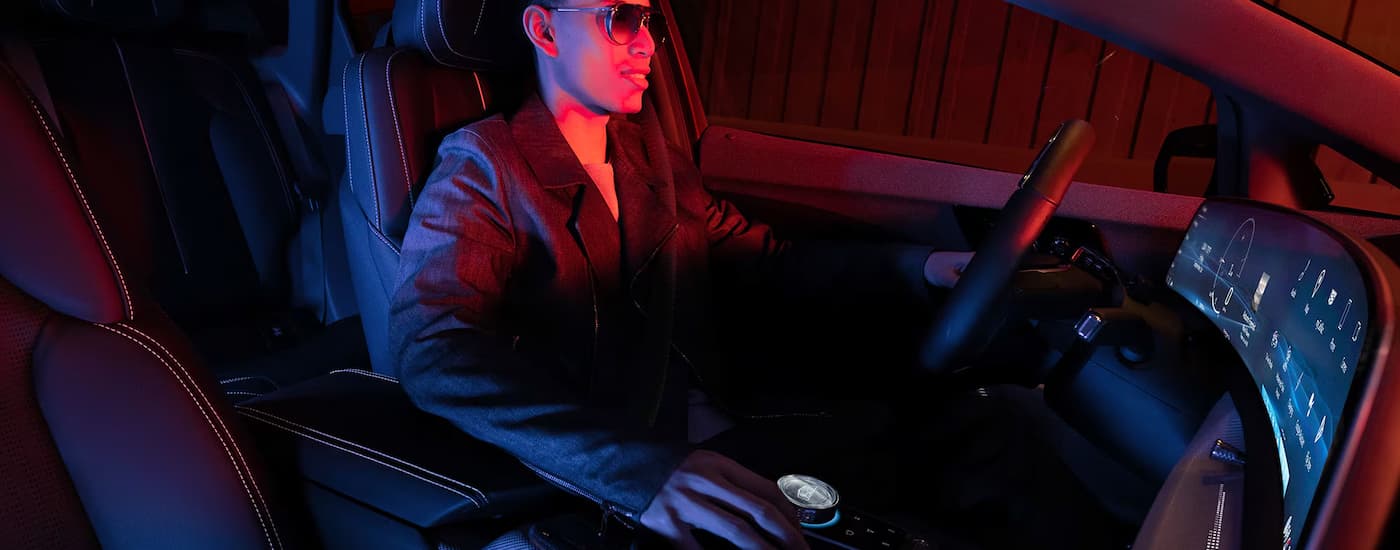 A man is sitting in the front seat of a 2025 Cadillac OPTIQ for sale.