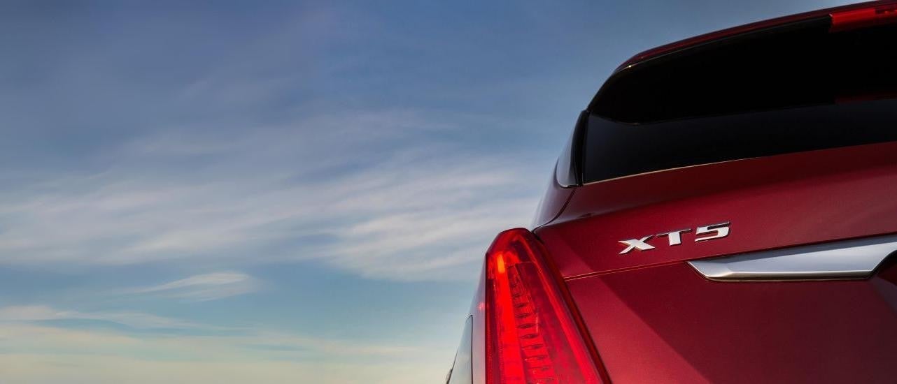 A red 2019 Cadillac XT5 is shown from the rear on a cloudy day.