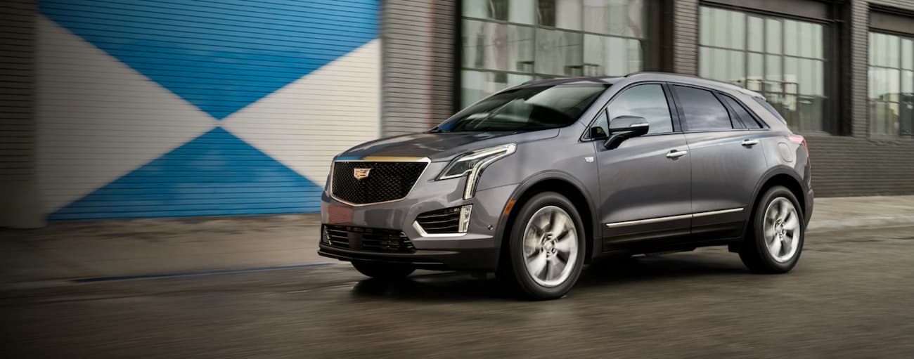 Silver 2021 Cadillac XT5 driving by a building.