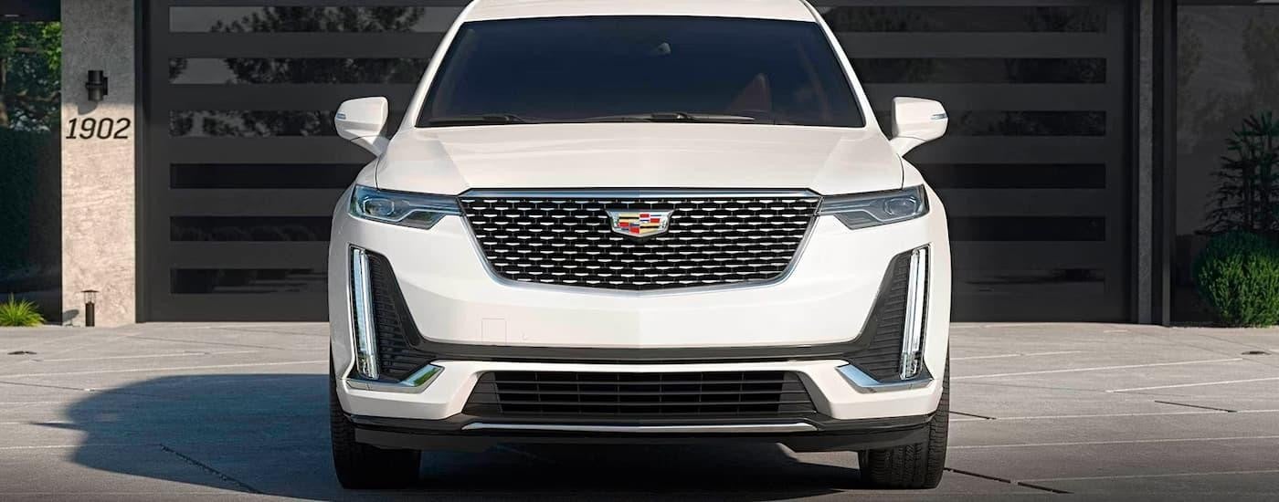 A white 2023 Cadillac XT6 for Sale is shown parked on a driveway outside of a garage door.