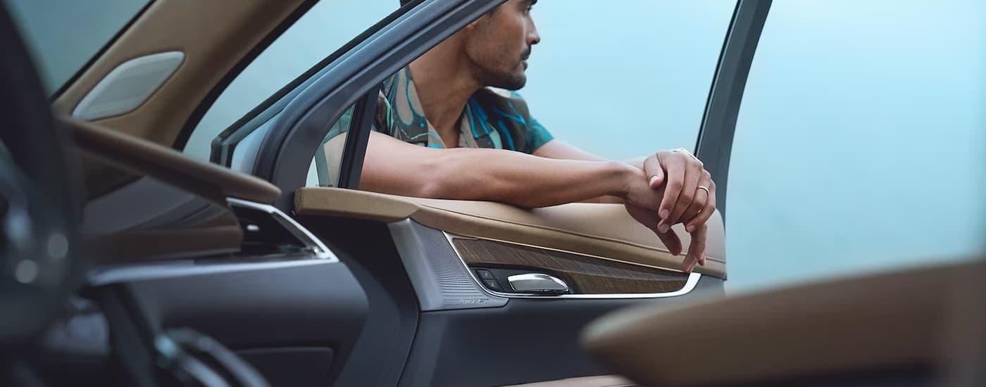 A man is shown leaning on the open window of a 2023 Cadillac XT6.