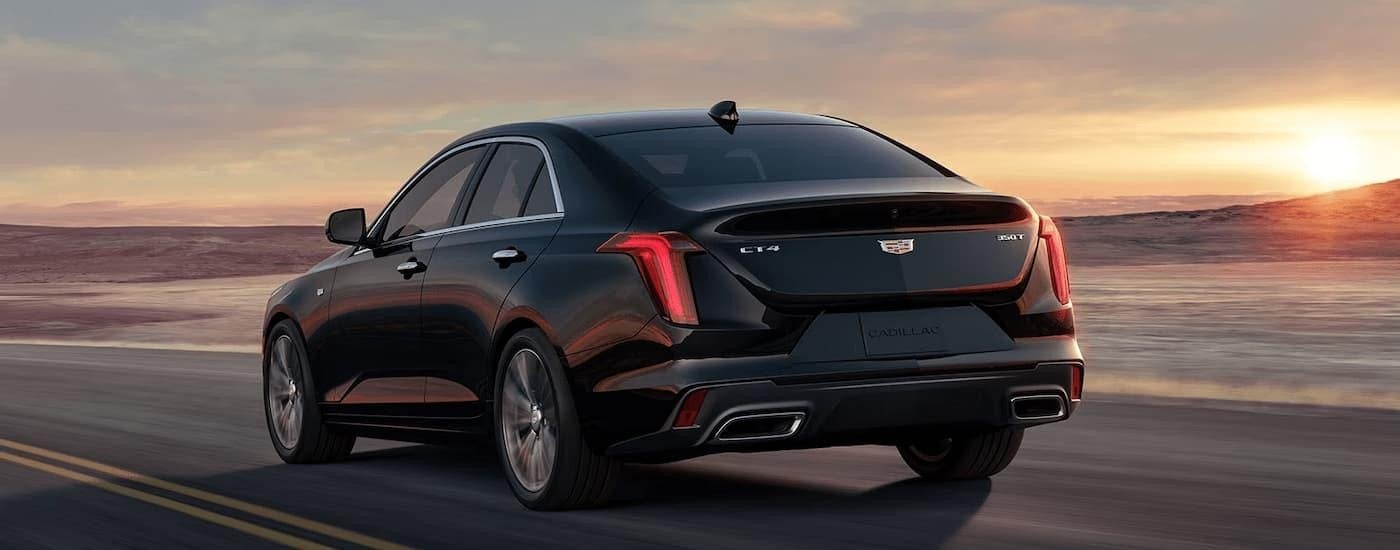 A black 2023 Cadillac CT4 is shown from the rear driving on an open highway.