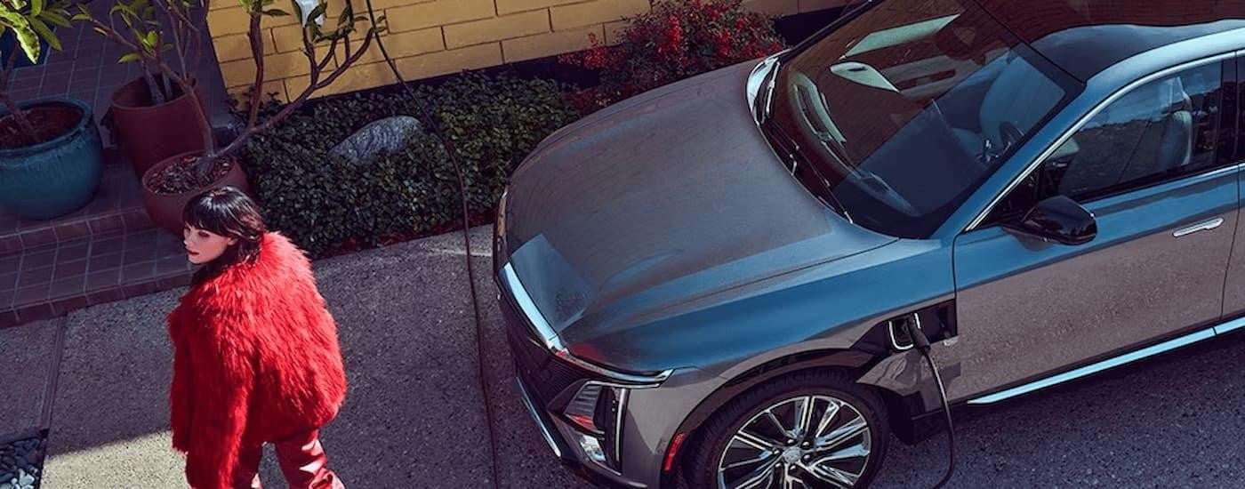 A silver 2023 Cadillac LYRIQ is shown parked and charging at an EV wall charging station.
