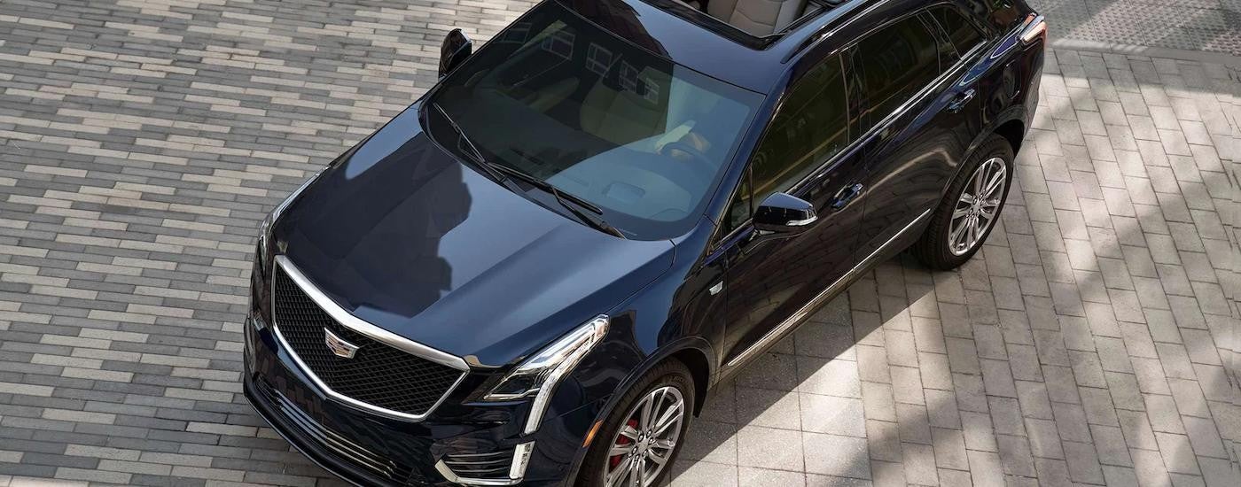 A blue 2022 Cadillac XT5 is parked on a stone driveway.