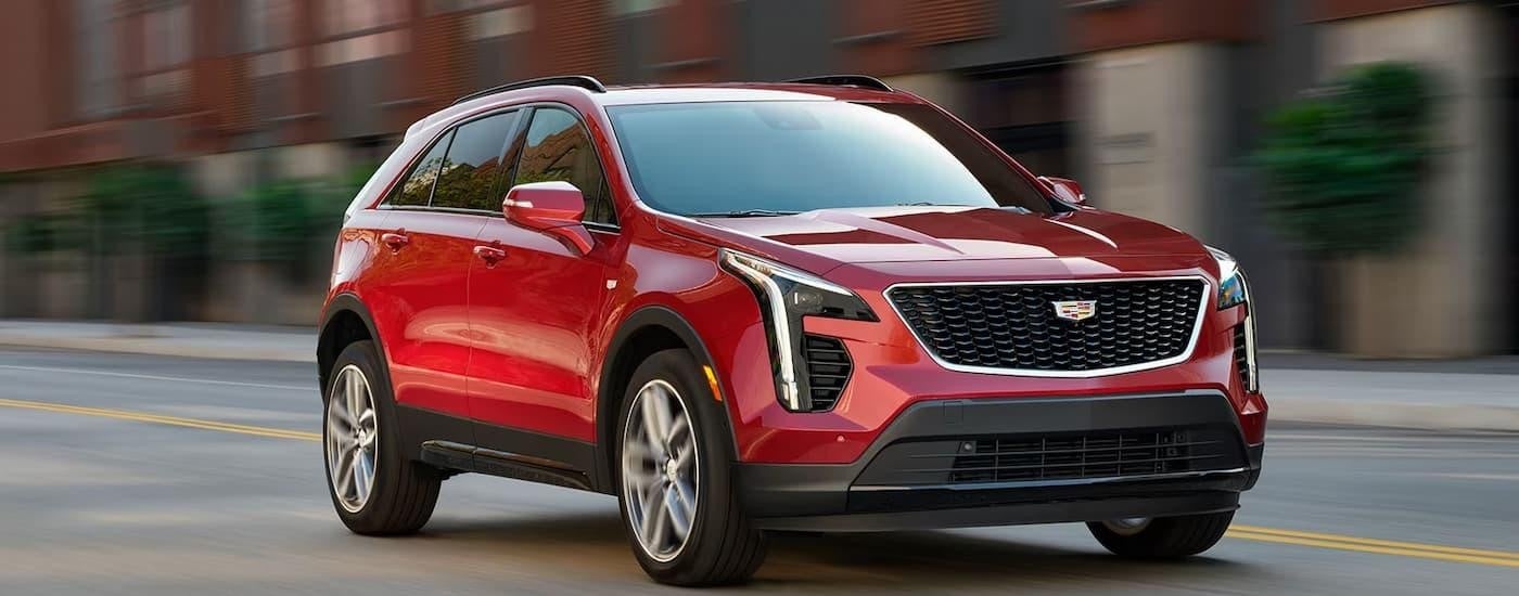 A red 2024 Cadillac XT4 is driving on a city street.