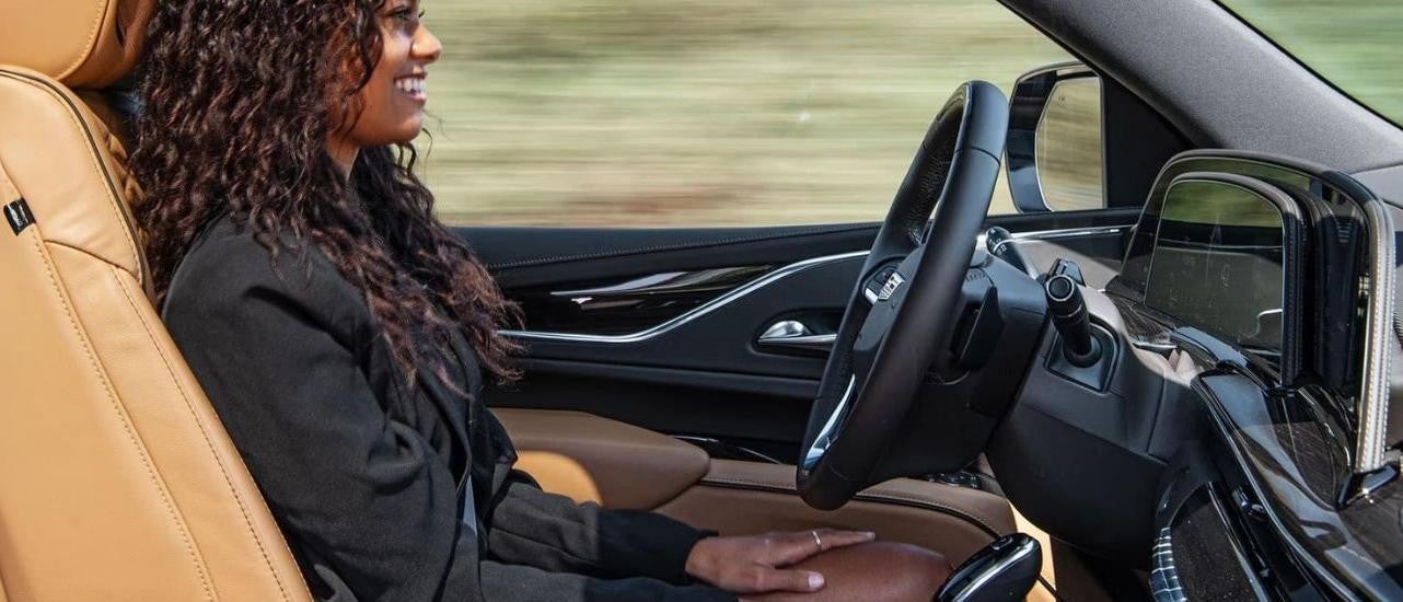 A person is shown using the Super Cruise feature in a 2023 Cadillac Escalade after looking at used SUVs for sale.